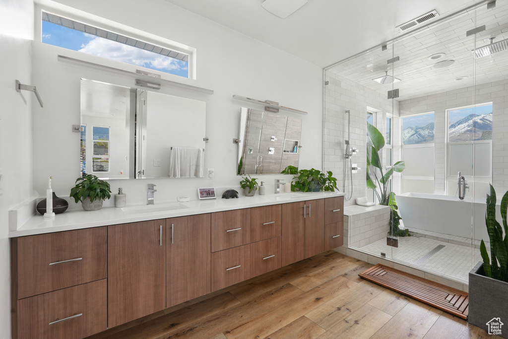 Bathroom featuring hardwood / wood-style flooring, oversized vanity, independent shower and bath, and plenty of natural light