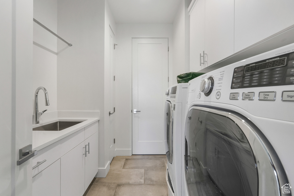 Laundry room with sink, independent washer and dryer, cabinets, and light tile floors