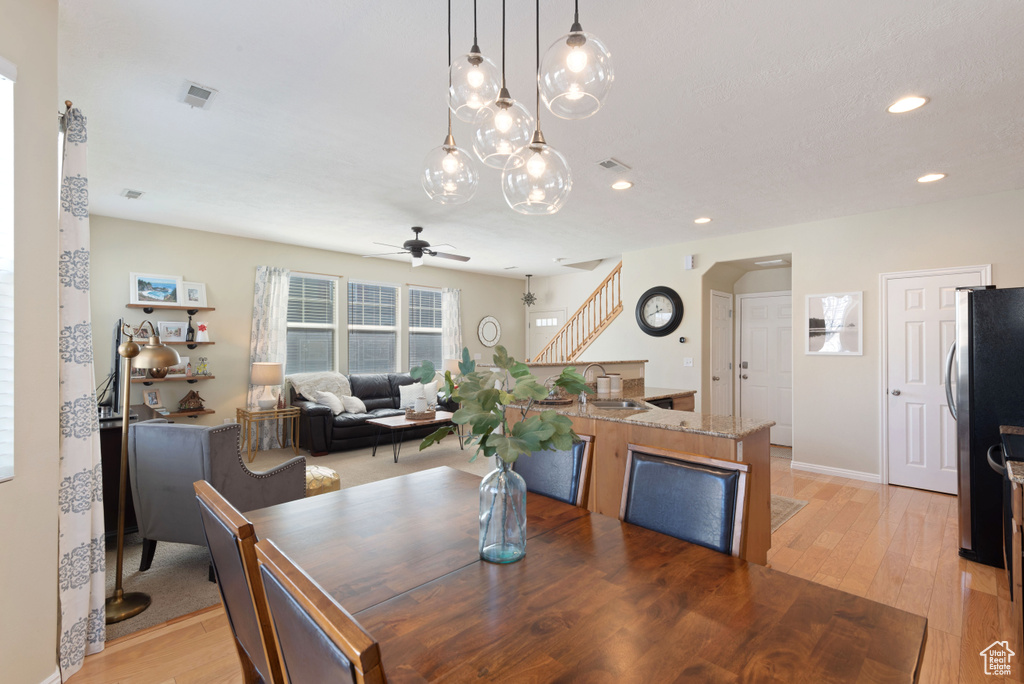 Dining space with sink, hardwood / wood-style flooring, and ceiling fan with notable chandelier
