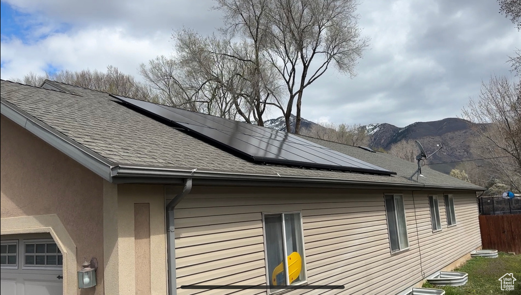 View of home\\\\\\\'s exterior with solar panels, a garage, and a mountain view