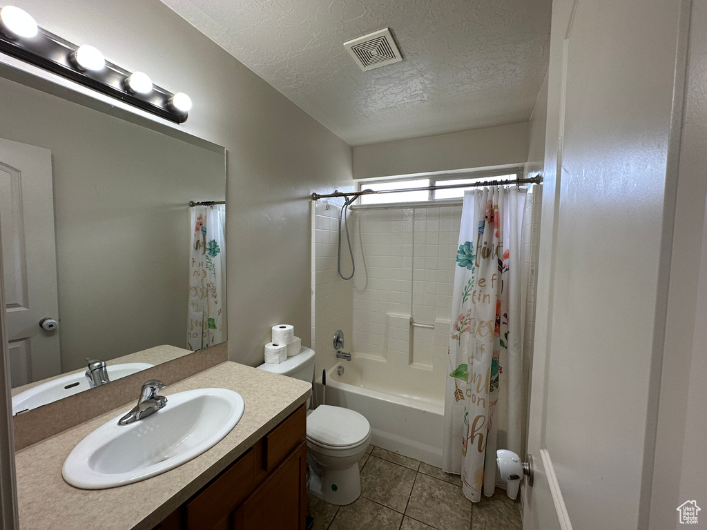 Full bathroom featuring toilet, tile flooring, a textured ceiling, shower / bathtub combination with curtain, and large vanity