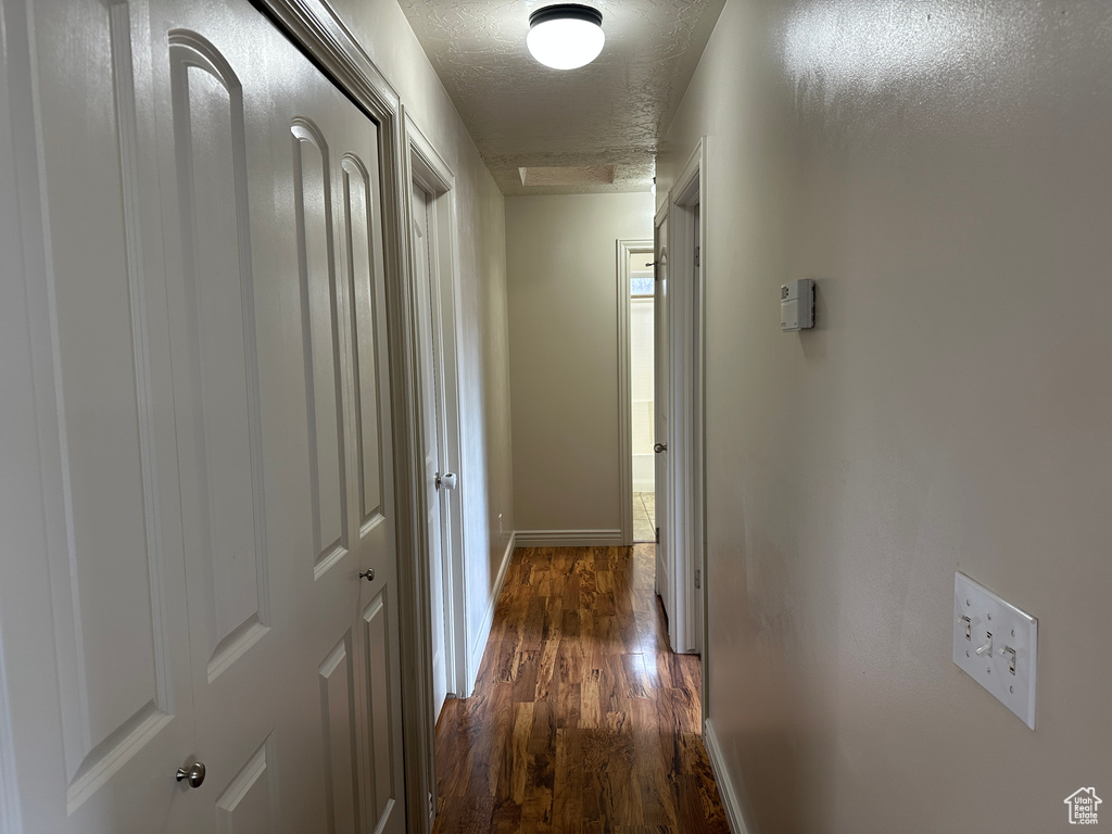 Corridor with a textured ceiling and dark wood-type flooring