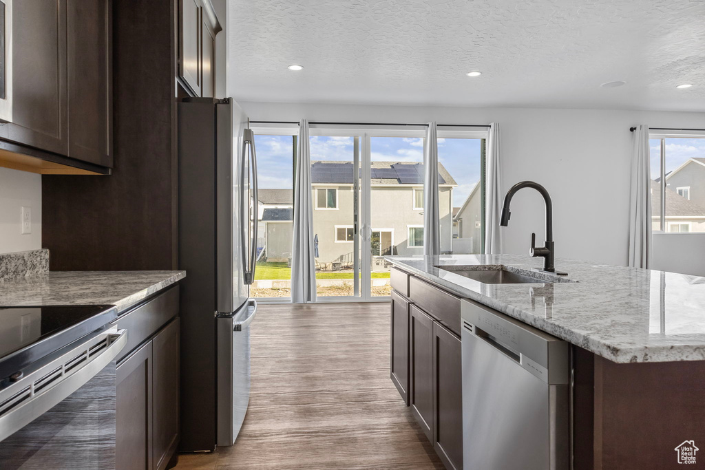 Kitchen featuring appliances with stainless steel finishes, a healthy amount of sunlight, hardwood / wood-style flooring, and sink