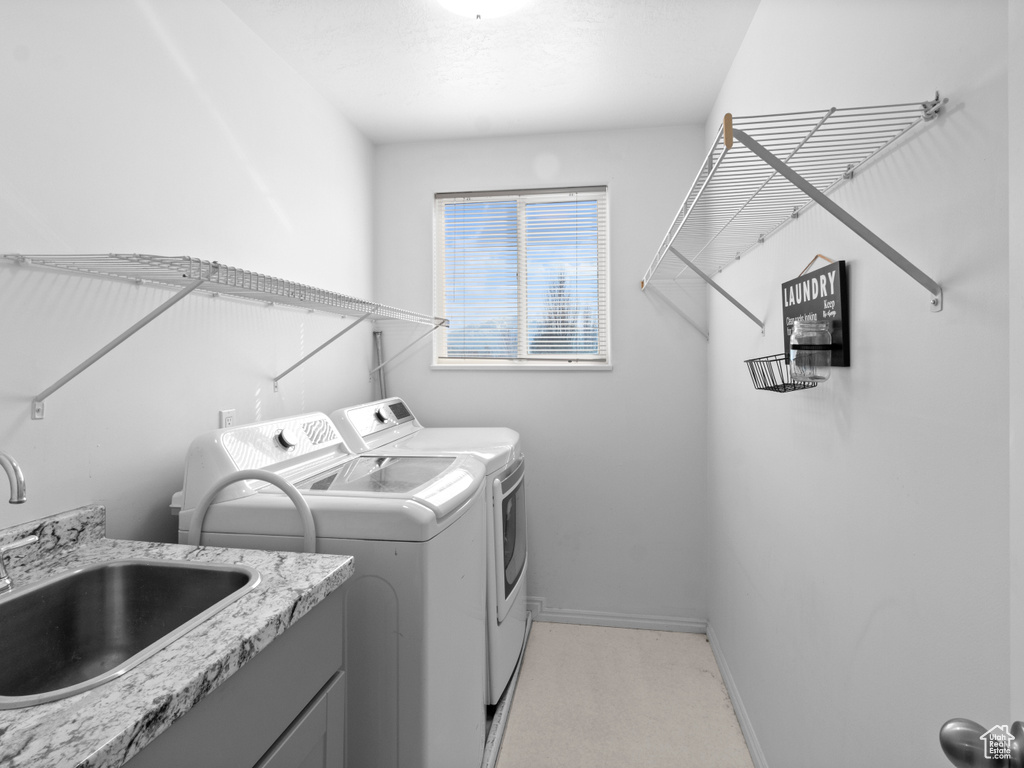 Clothes washing area with sink and washer and dryer
