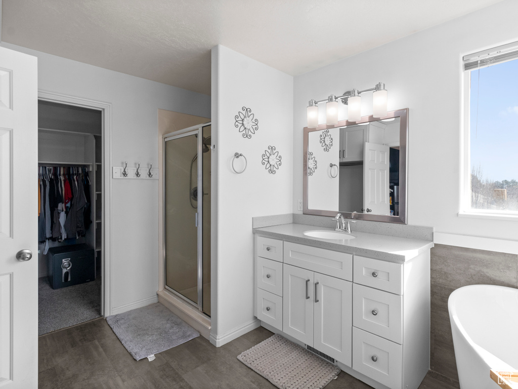 Bathroom featuring shower with separate bathtub, vanity, and wood-type flooring