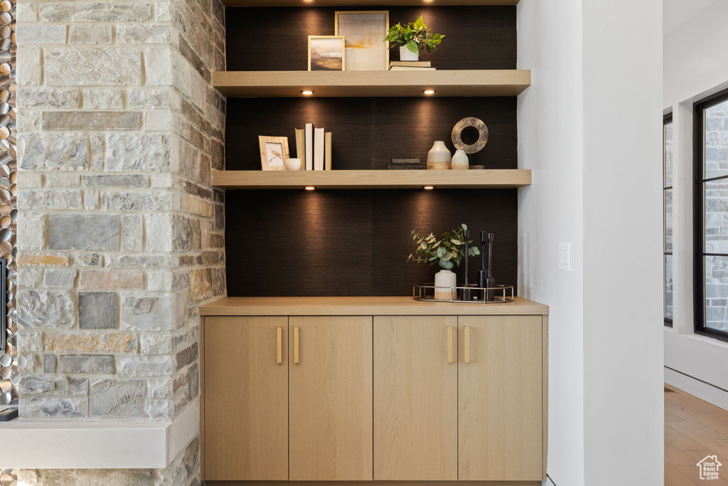 Bar featuring light brown cabinetry and light hardwood / wood-style floors
