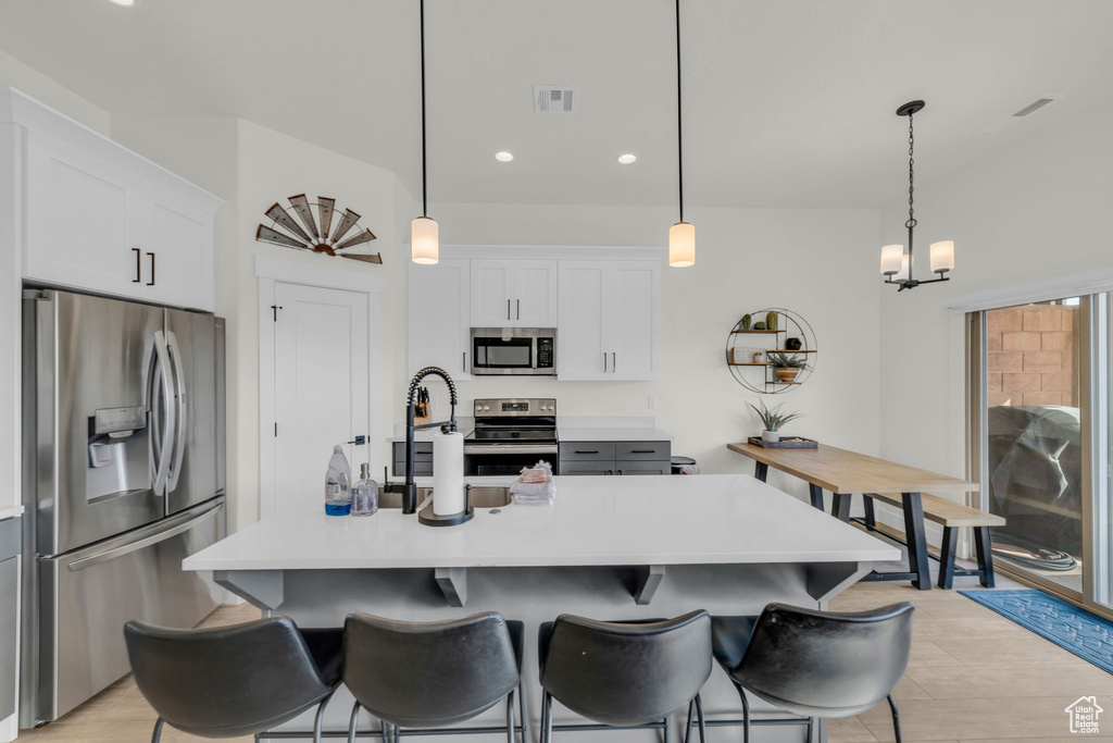 Kitchen with a notable chandelier, light hardwood / wood-style floors, stainless steel appliances, and decorative light fixtures
