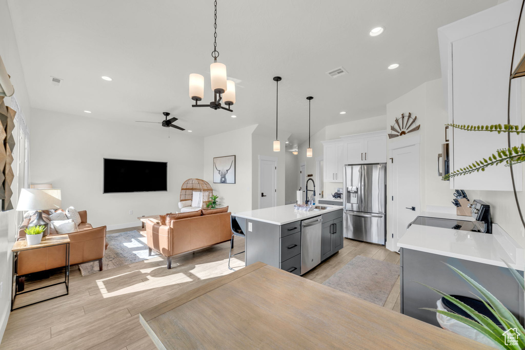 Interior space with light hardwood / wood-style flooring, sink, and ceiling fan with notable chandelier