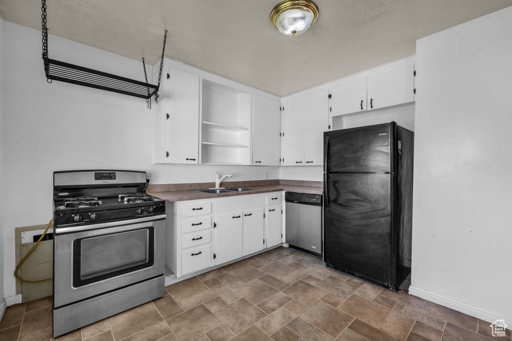 Kitchen featuring white cabinets, dark tile flooring, appliances with stainless steel finishes, and sink