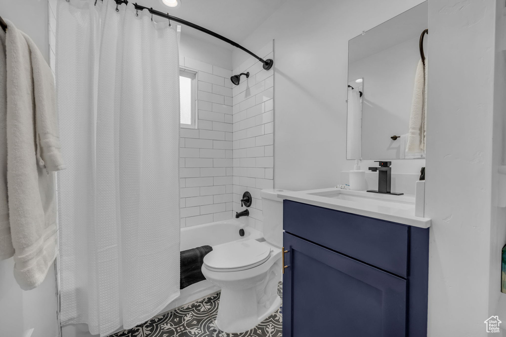 Full bathroom with toilet, vanity, tile floors, and shower / tub combo