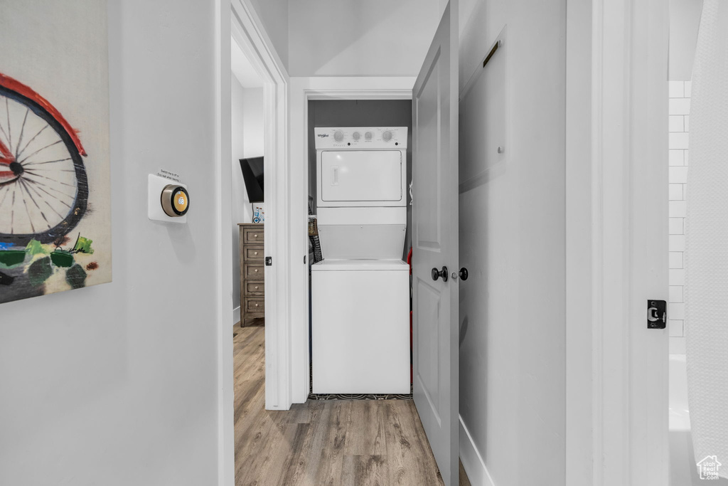 Hall featuring stacked washer and clothes dryer and light hardwood / wood-style floors