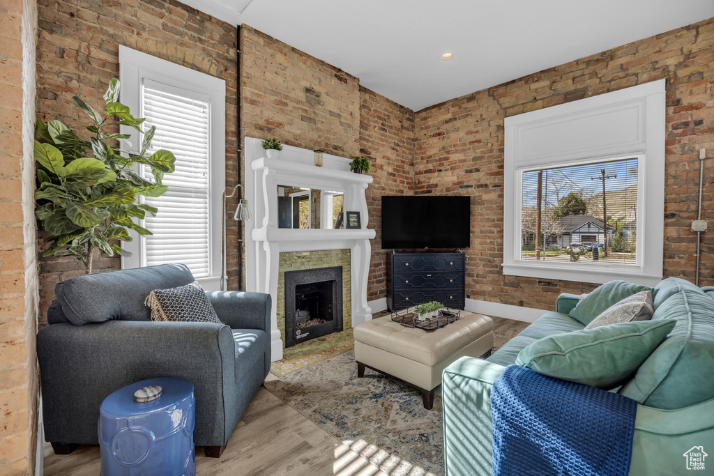Living room with plenty of natural light, brick wall, and light hardwood / wood-style flooring