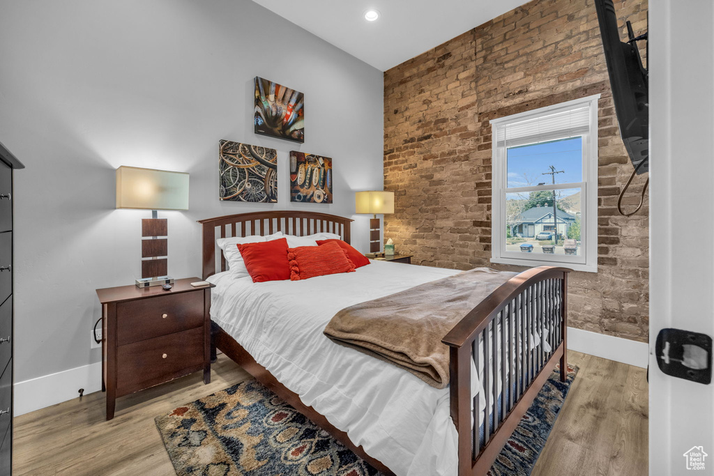Bedroom featuring brick wall and light hardwood / wood-style floors
