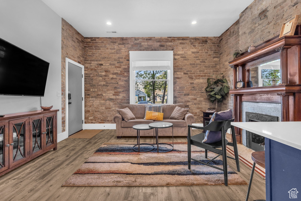 Living room featuring brick wall, wood-type flooring, and a wealth of natural light