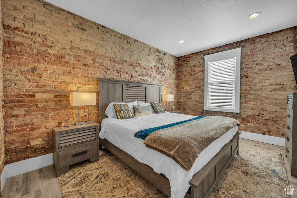 Bedroom with brick wall and light wood-type flooring