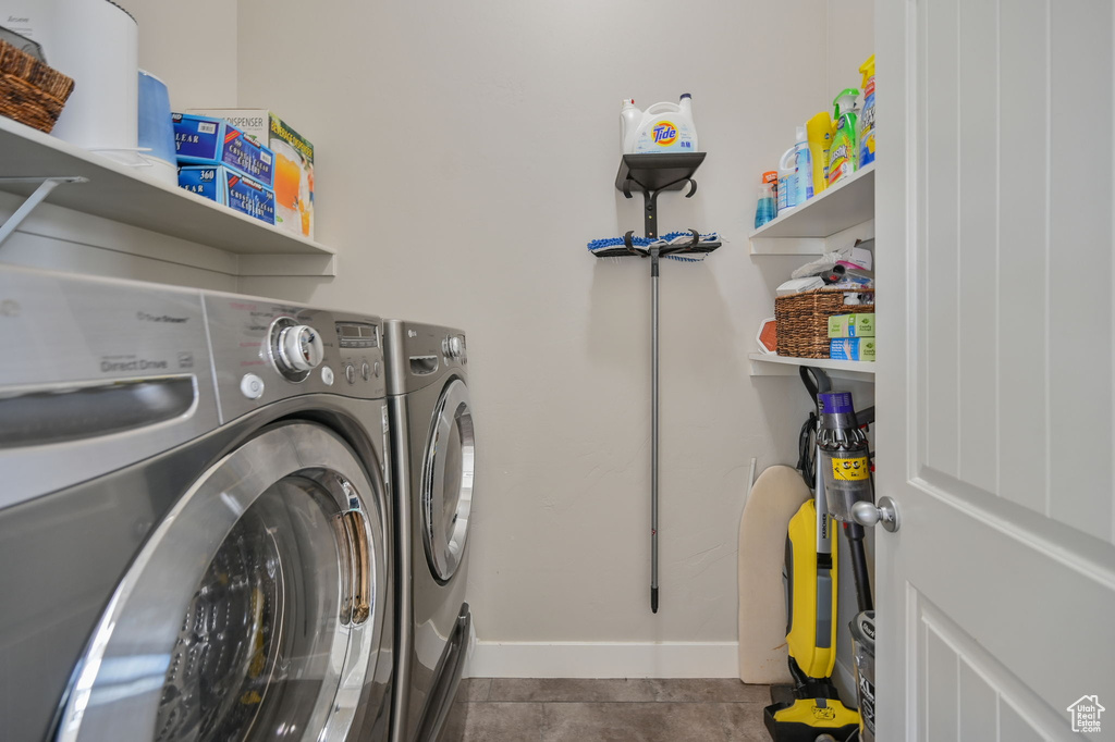Clothes washing area with dark tile floors and separate washer and dryer