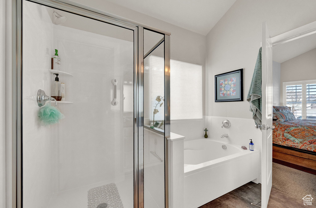 Bathroom with hardwood / wood-style flooring, shower with separate bathtub, and lofted ceiling