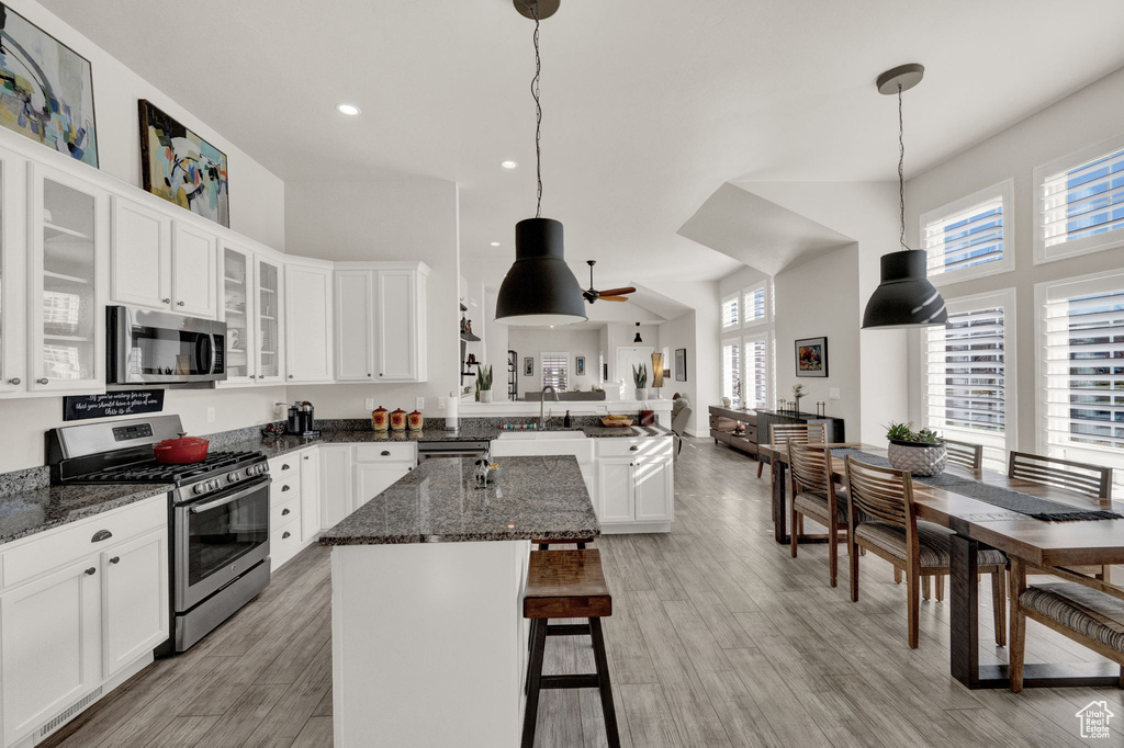 Kitchen with white cabinetry, appliances with stainless steel finishes, a center island, and pendant lighting