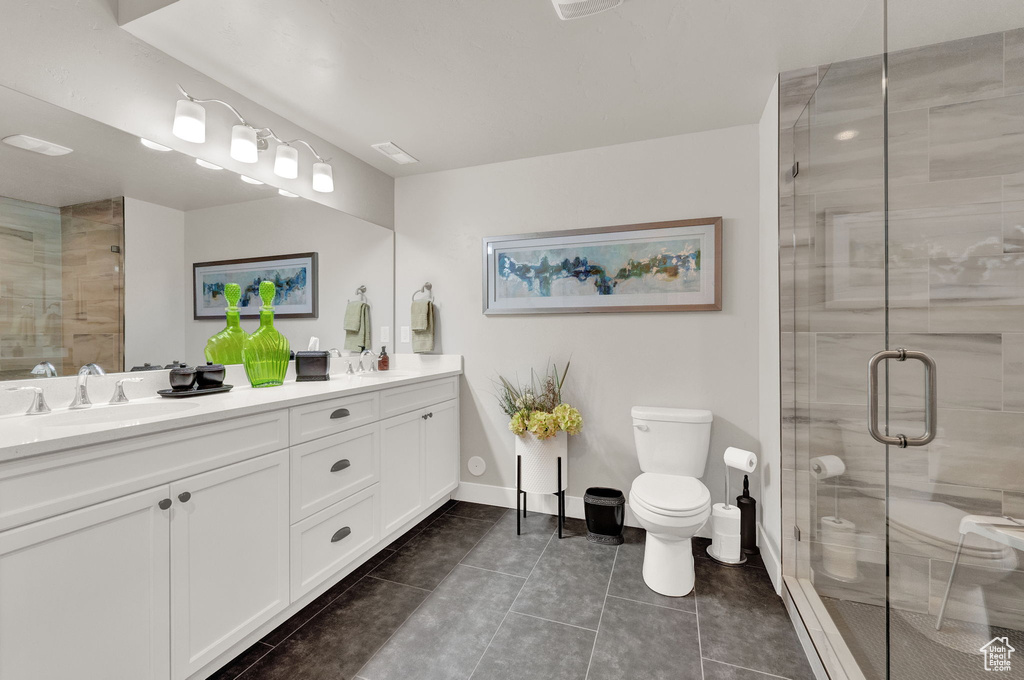 Bathroom featuring toilet, tile floors, double sink vanity, and walk in shower