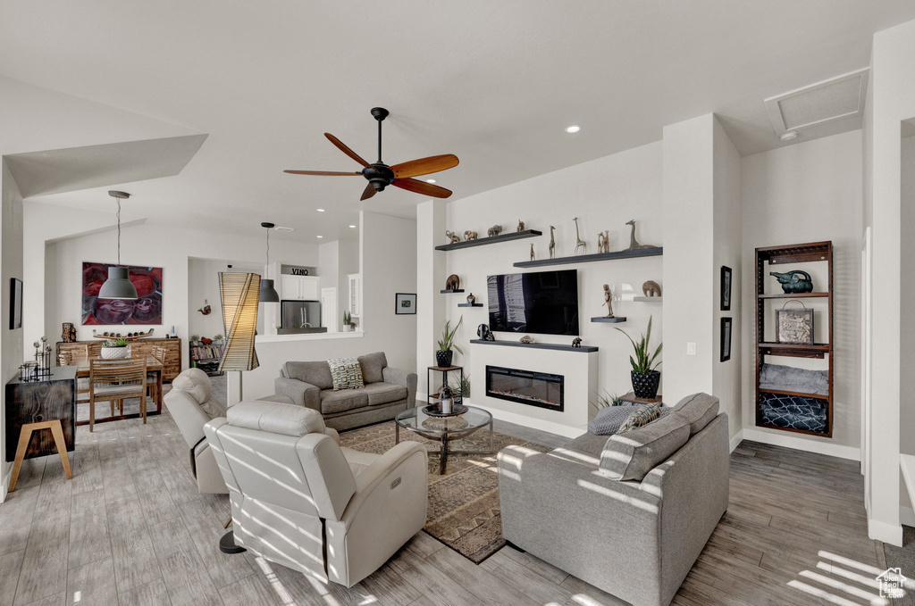 Living room with ceiling fan, light hardwood / wood-style flooring, and vaulted ceiling