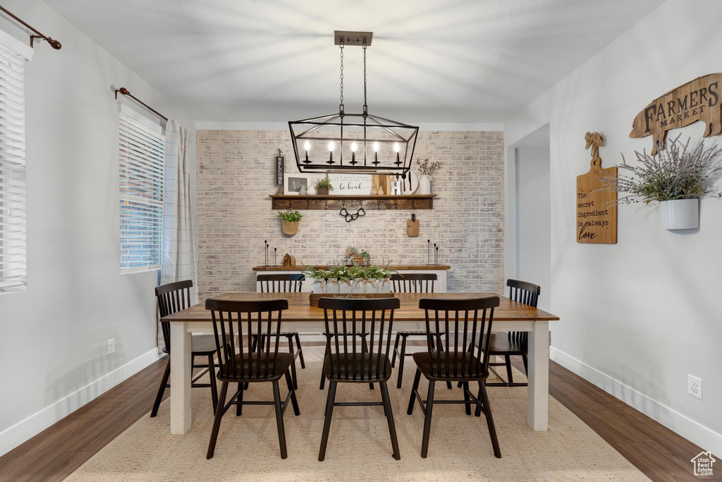 Dining room featuring a chandelier, brick wall, and dark hardwood / wood-style flooring
