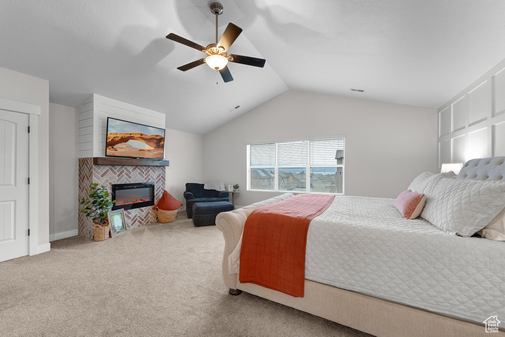 Carpeted bedroom featuring ceiling fan, a tile fireplace, and lofted ceiling