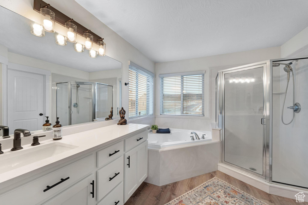 Bathroom with hardwood / wood-style floors, shower with separate bathtub, and large vanity