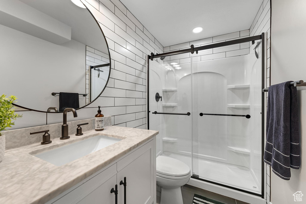 Bathroom with a shower with door, vanity with extensive cabinet space, and toilet