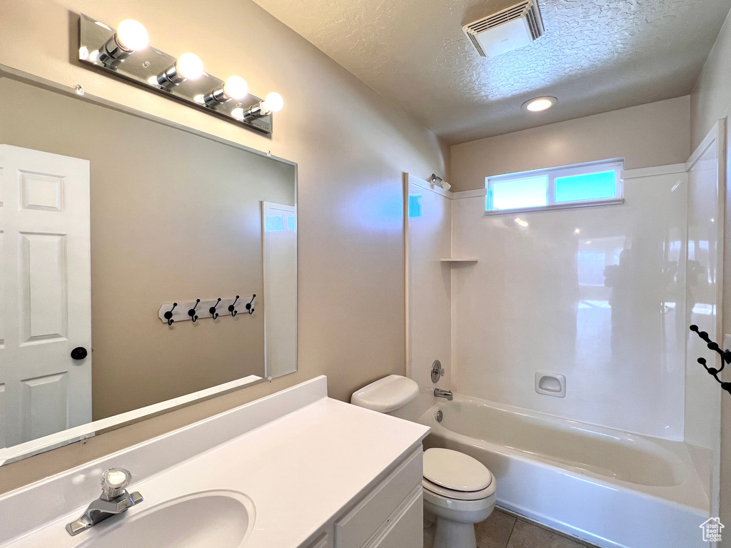 Full bathroom featuring toilet, shower / bathtub combination, a textured ceiling, large vanity, and tile floors