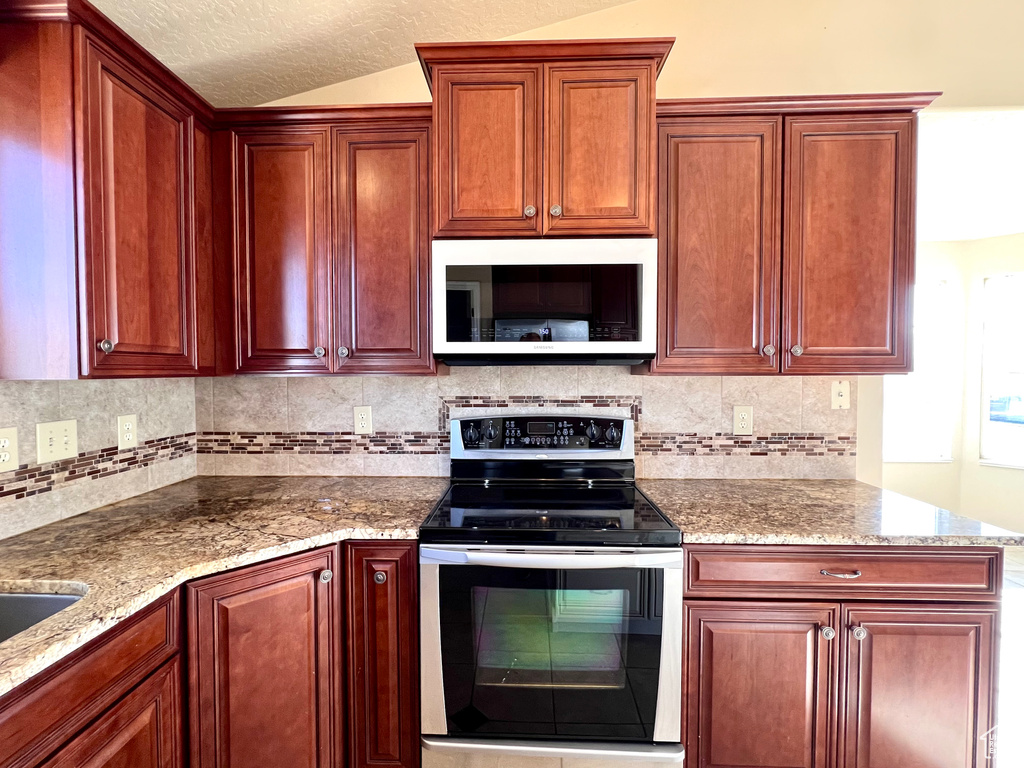 Kitchen with backsplash, stainless steel electric range, and light stone countertops