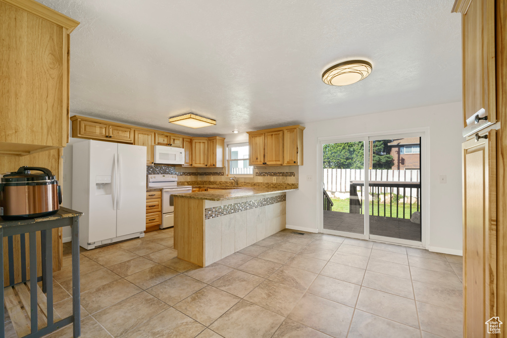 Kitchen featuring light tile floors, sink, white appliances, tasteful backsplash, and kitchen peninsula