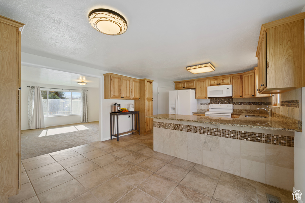 Kitchen featuring white appliances, tasteful backsplash, light stone counters, sink, and light tile floors