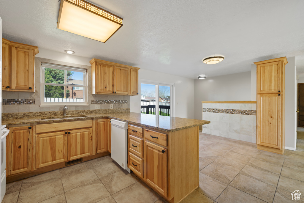 Kitchen featuring white appliances, light stone countertops, light tile flooring, and kitchen peninsula