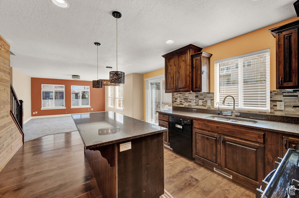 Kitchen featuring dishwasher, backsplash, sink, light hardwood / wood-style flooring, and decorative light fixtures