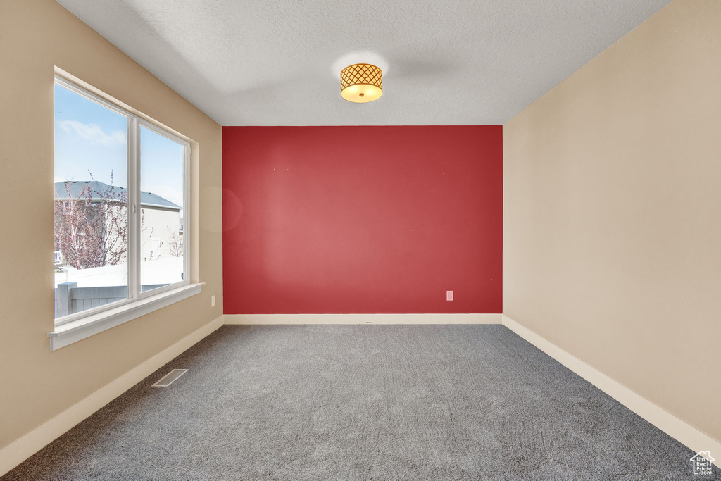 Spare room with a textured ceiling and dark colored carpet