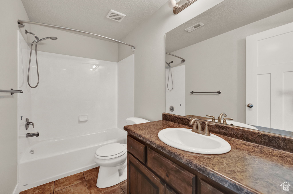 Full bathroom with tile flooring,  shower combination, a textured ceiling, toilet, and oversized vanity