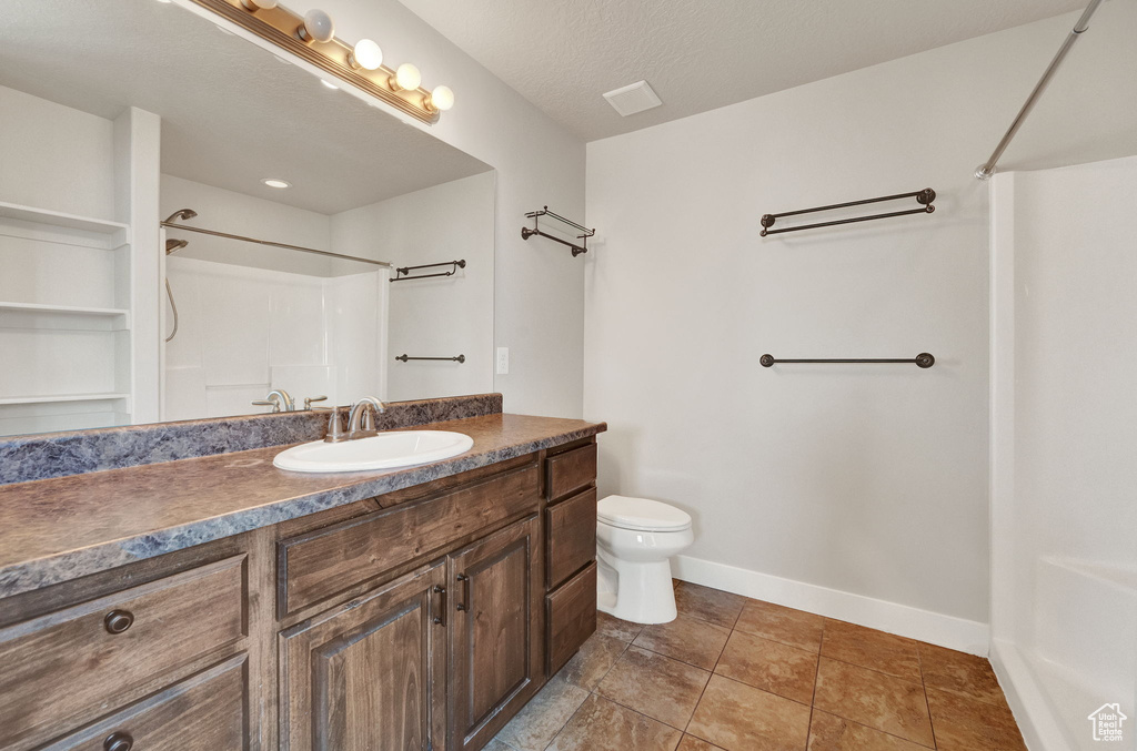 Bathroom featuring a textured ceiling, tile flooring, toilet, and vanity