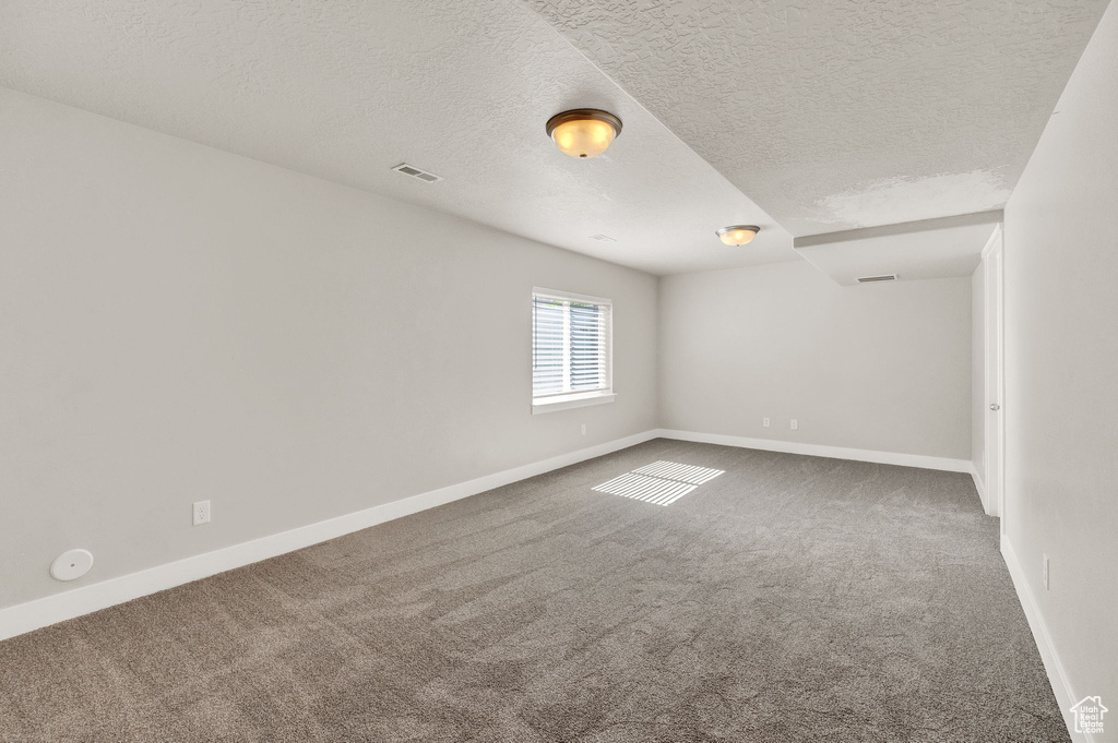 Spare room featuring a textured ceiling and dark colored carpet
