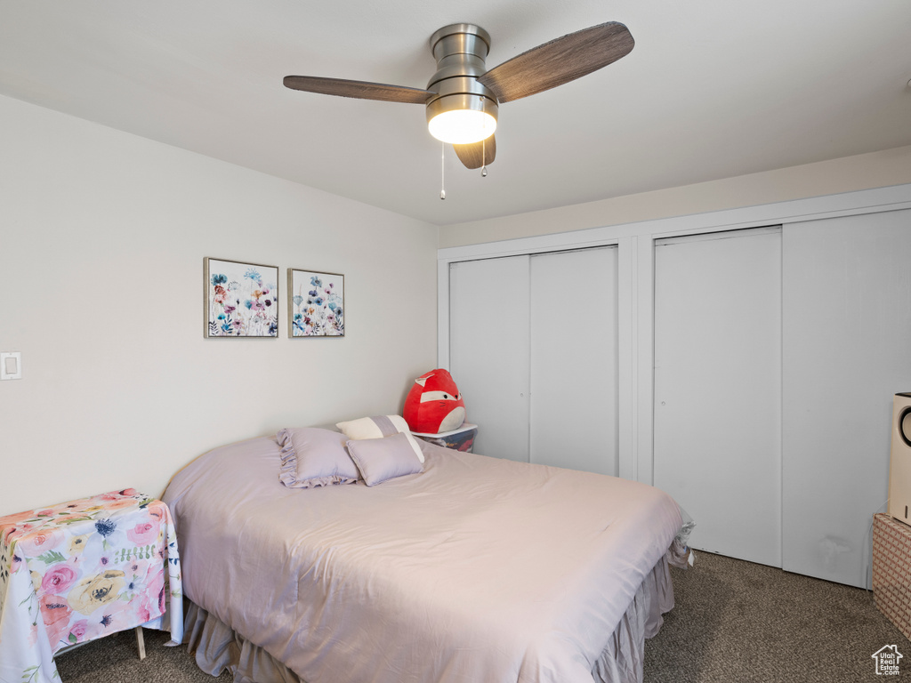 Bedroom featuring ceiling fan, dark carpet, and multiple closets