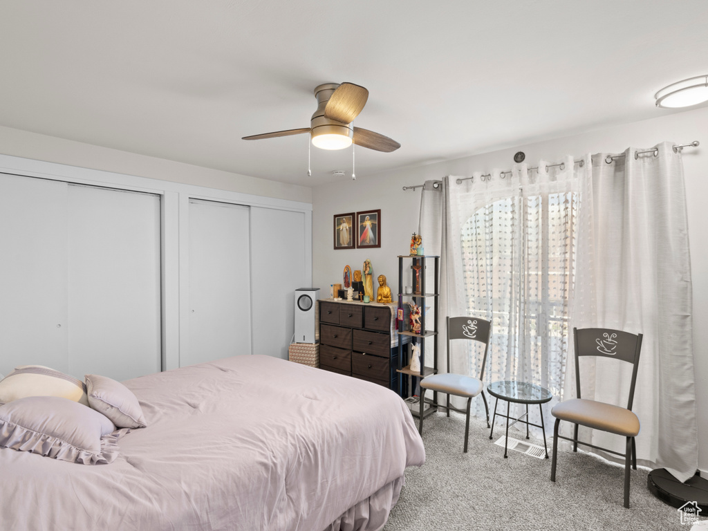 Bedroom featuring ceiling fan, two closets, and light colored carpet