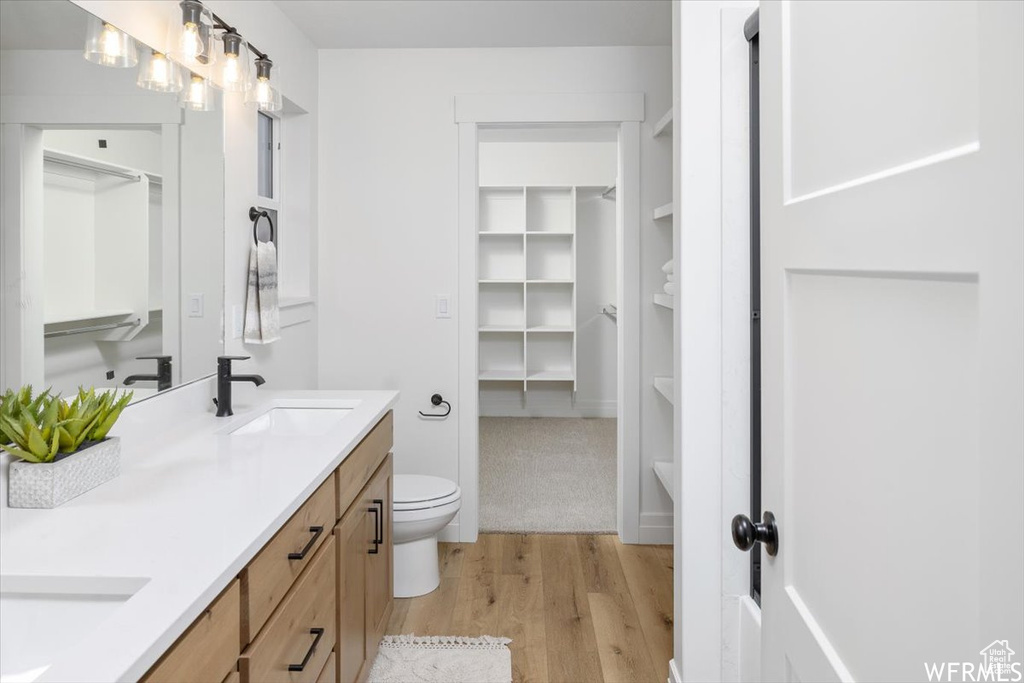 Bathroom with toilet, hardwood / wood-style flooring, and dual bowl vanity