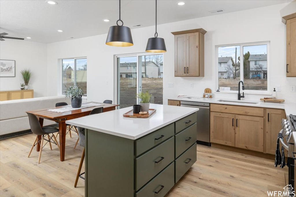 Kitchen featuring dishwasher, sink, light hardwood / wood-style floors, a kitchen island, and decorative light fixtures