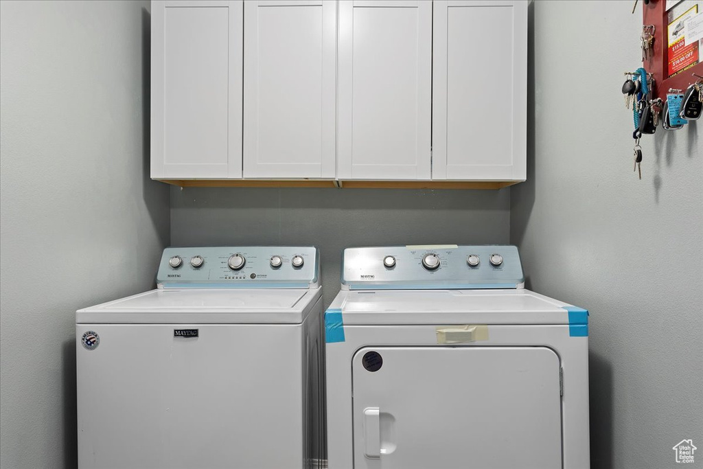 Washroom featuring washing machine and clothes dryer and cabinets