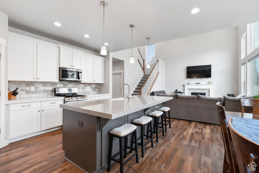 Kitchen featuring dark hardwood / wood-style flooring, stainless steel appliances, white cabinets, and hanging light fixtures