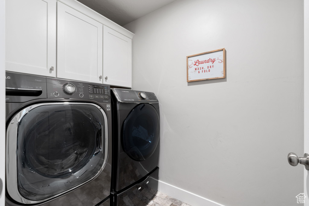 Laundry area featuring light tile flooring, cabinets, and washer and clothes dryer