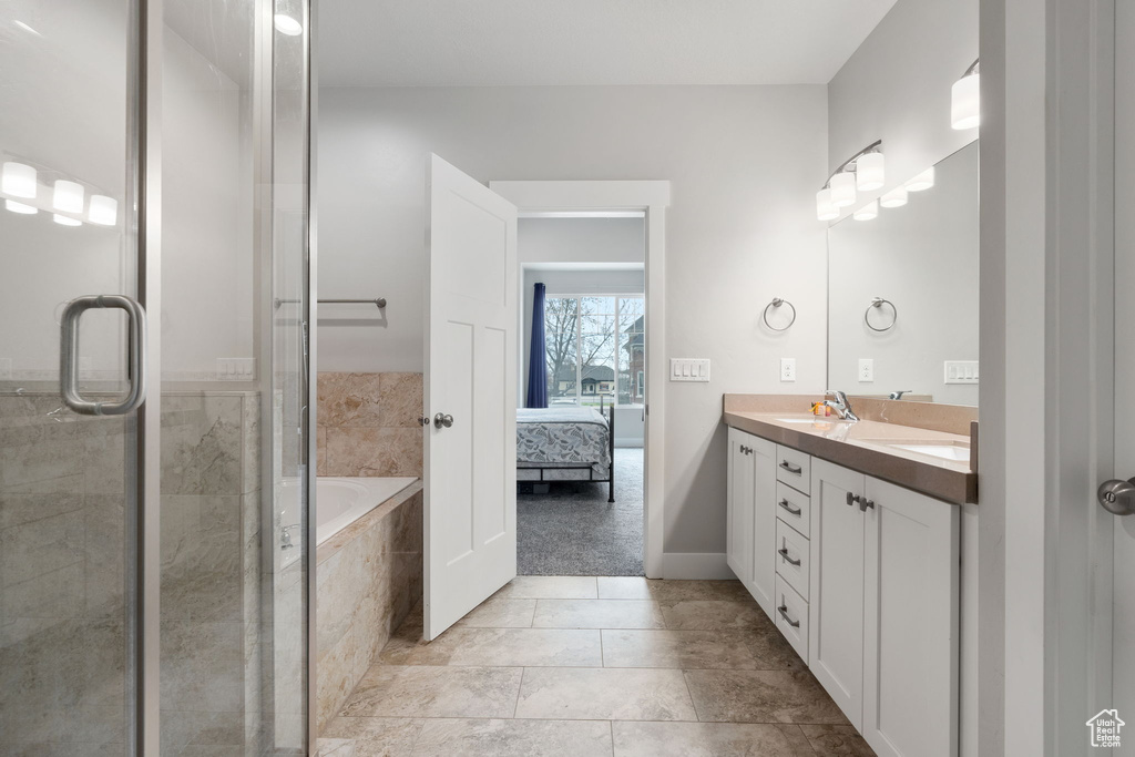 Bathroom featuring double sink vanity, plus walk in shower, and tile floors