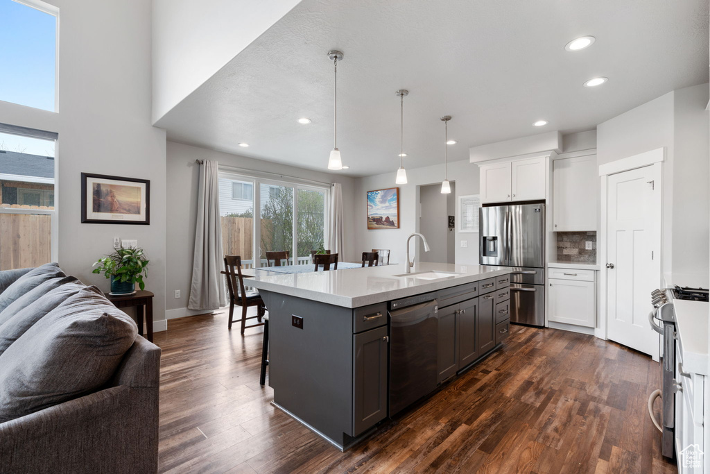 Kitchen featuring appliances with stainless steel finishes, sink, dark wood-type flooring, and white cabinets