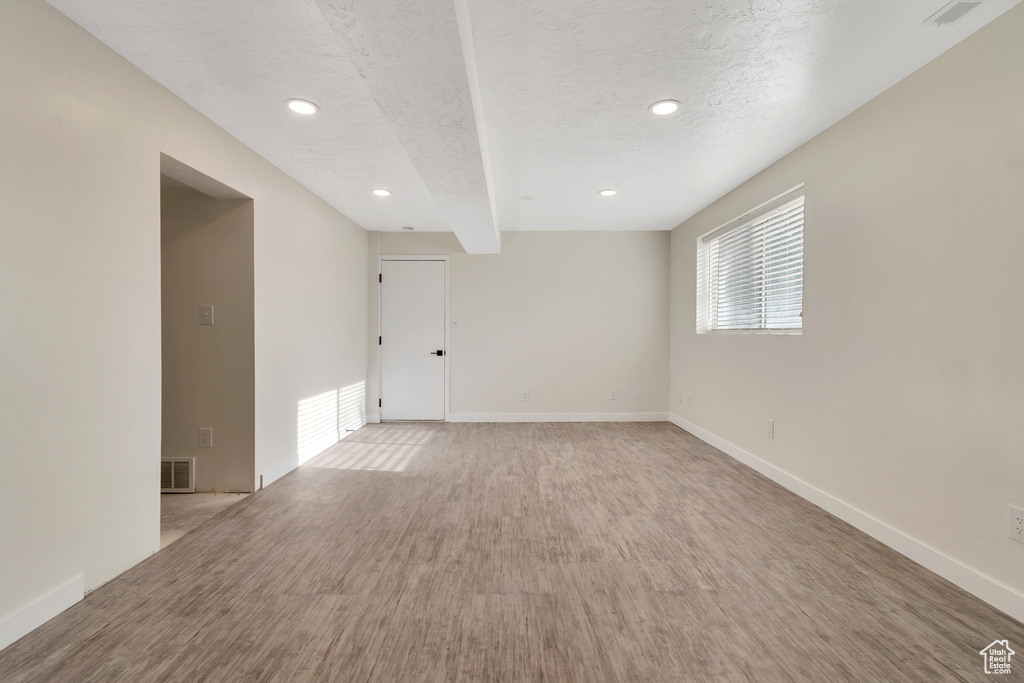 Spare room with beam ceiling and light hardwood / wood-style floors