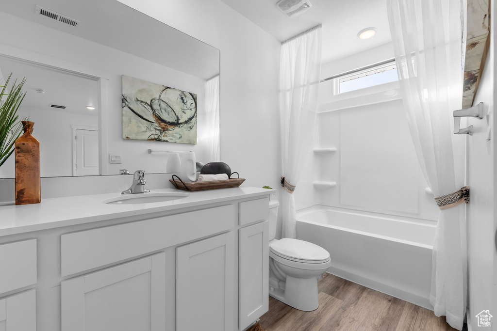 Full bathroom with toilet, vanity, hardwood / wood-style flooring, and shower / tub combo with curtain