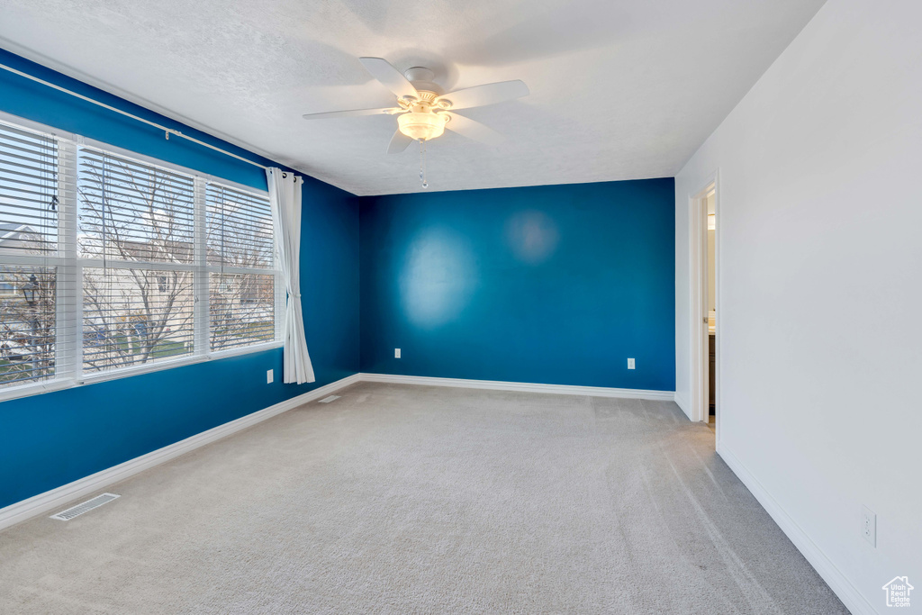 Spare room featuring ceiling fan, a textured ceiling, and light colored carpet
